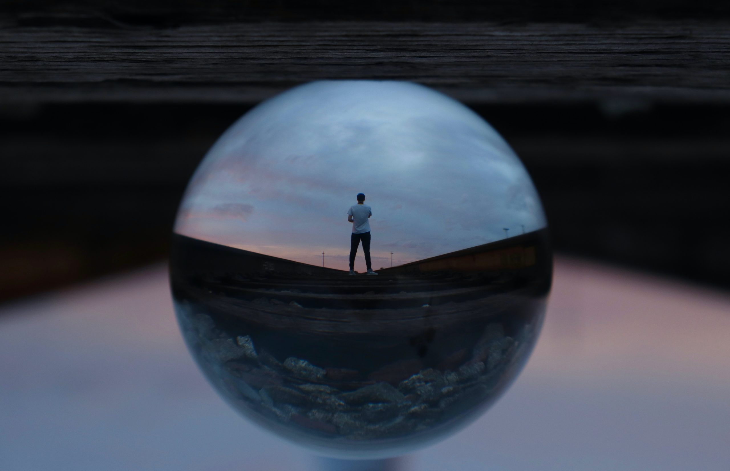 This image shows a person standing with proud body-language in nature, reflected in a ball